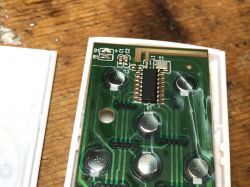 Close-up of a remote control circuit board with several buttons and an integrated circuit.