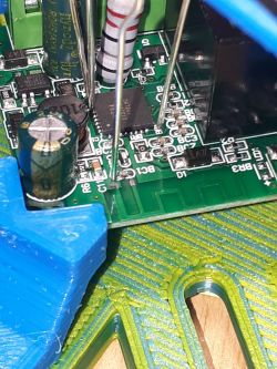 Close-up of a circuit board with visible electronic components and a needle probe.