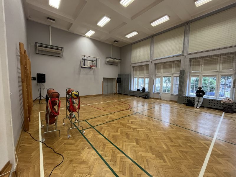 Ustawienie nagłośnienia w sali gimnastycznej do występu teatralnego Sala gimnastyczna z głośnikami ustawionymi w rogach i mikrofonami poza kadrem