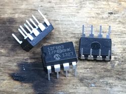 PIC12F683 Microcontrollers on Surface Three PIC12F683 microcontrollers on a wooden surface.