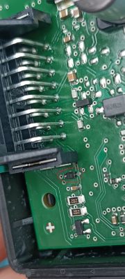 Zbliżenie na płytkę PCB modułu elektronicznego z uszkodzonym czarnym elementem SMD oznaczonym „AM”.