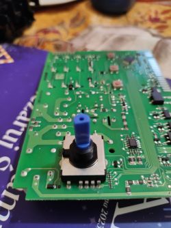 Zbliżenie na płytkę elektroniczną ze zmywarki z niebieskim enkoderem.