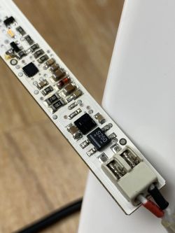 Zbliżenie na płytkę elektroniczną lampki LED z widocznymi komponentami i przewodami.