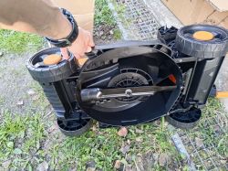 Spód elektrycznej kosiarki Ondragon z widocznym nożem tnącym i kołami, trzymanej przez osobę.