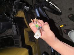 Zbliżenie na rękę trzymającą złącze elektryczne z kilkoma przewodami przy rowerze.