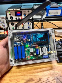 GPS Device Prototype with Satellite and LTE Communication GPS device in a transparent case with an OLED display and three blue batteries.