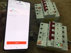 3-Phase Tuya Energy Meter and Smartphone Smartphone displaying successfully added Tuya device next to two 3-phase energy meters.