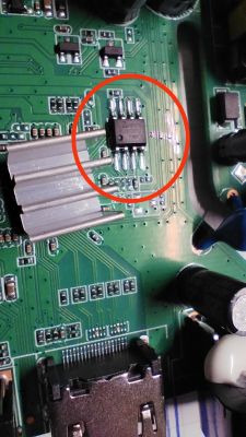 Zaznaczony układ scalony SMD na zielonym obwodzie drukowanym z radiatorem obok.