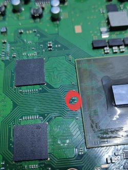 Zbliżenie na płytę główną PS3 z zaznaczonym miejscem lutowniczym bez elementu