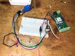 Electronic module with a breadboard and wires on a wooden surface.