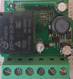 Close-up of a green circuit board with electronic components such as resistors, capacitors, and a relay.