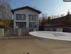 Nowoczesny dwupiętrowy dom z ogrodzeniem przy ulicy, obok zabudowania i zaparkowanego auta