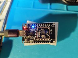 An electronic module with a connected USB cable, featuring illuminated LEDs.