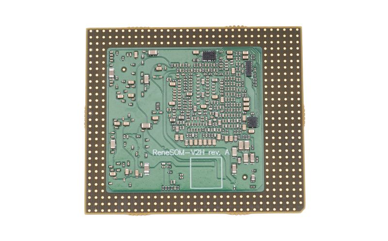 Underside of an IC module with green PCB and grid of gold pads; text “ReneSOM‑V2H rev. A”.