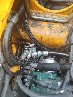Fragment układu hydraulicznego ładowarki teleskopowej JCB 541-70, widoczne przewody, złączki i pompa.