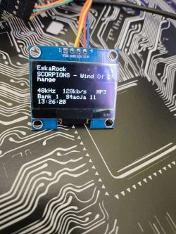 Small OLED display showing music track information and sound parameters.
