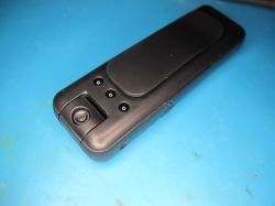 Miniature spy camera with clip Black mini spy camera with clip on a blue surface
