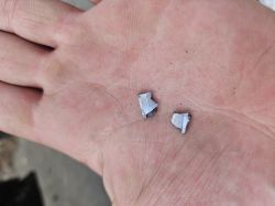 Dwa kawałki aluminium na otwartej, lekko zabrudzonej dłoni.