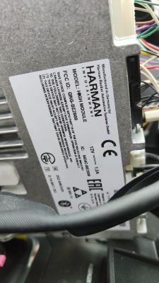 Radio samochodowe Harman z widocznymi wtyczkami i przewodami.