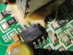 Zbliżenie na układ scalony na zielonej płytce PCB z elementami SMD i białą żywicą.