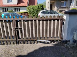 Dwuskrzydłowa brama wjazdowa z drewnianymi sztachetami i ramką z profila.