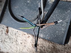 Końcówki przewodów elektrycznych z różnymi kolorami na tle betonowej powierzchni.