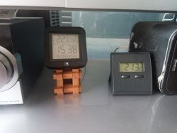 Two devices with LCD displays showing different temperature readings on a desk.