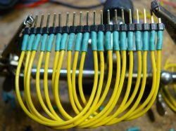 Żółte przewody połączone z pinami, zabezpieczone niebieskimi koszulkami termokurczliwymi.