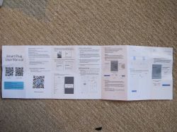 Smart Plug User Manual A smart plug user manual lies on the carpet, instructions are written in English.