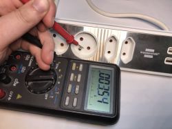 Multimetr mierzący napięcie w przedłużaczu z gniazdami USB.