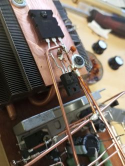 Zbliżenie na ręcznie zbudowany wzmacniacz audio z zamontowanymi tranzystorami i radiatorami.