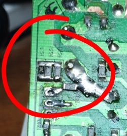 Close-up of damaged PCB with resistor labeled 2R0 highlighted in red circle