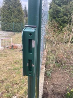 Pionowe zdjęcie zielonego słupka metalowego ogrodzenia z miejscem na zamontowanie elektrozaczepu.