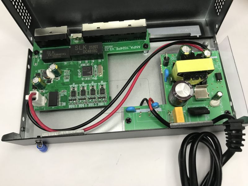 Inside a metal PoE switch case with two PCBs, wiring, and a separate power-supply board