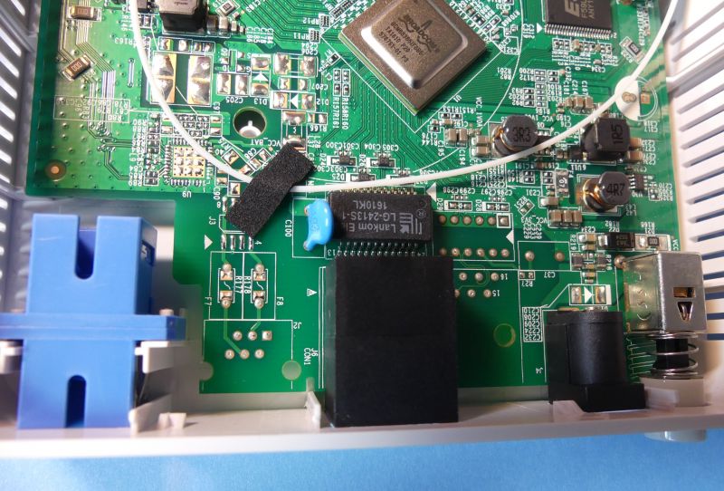 Wnętrze urządzenia ONT GPON z widocznymi elementami takimi jak pigtail, złącze SC, układy scalone Broadcom, port RJ45 i zasilanie.