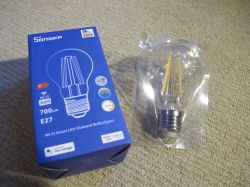 Sonoff B02-F-A60 LED filament bulb and its original packaging on a carpet.
