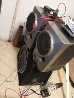 Zestaw głośników stereo i subwoofera z przewodami i elektronarzędziem na podłodze.