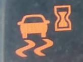 Kontrolki na desce rozdzielczej samochodu: symbol samochodu z falującymi liniami oraz klepsydra.