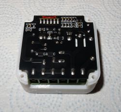 Bottom view of a PCB in a white plastic enclosure with mounted SMD components