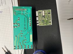 Dwie płytki PCB na biurku: większa z widocznymi ścieżkami i mniejsza z elementami oraz złączami