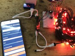 Controlling WS2812 LED Lighting with a Smartphone Smartphone with control app and glowing red WS2812 LEDs on a table.