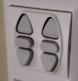 Wall-Mounted Shade Control Buttons White wall-mounted triangular buttons for controlling shades.
