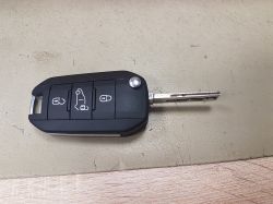 Czarny kluczyk samochodowy z trzema przyciskami leży na powierzchni stołu.