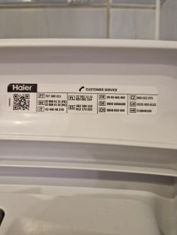 Zdjęcie naklejki z numerami serwisowymi pralki Haier.