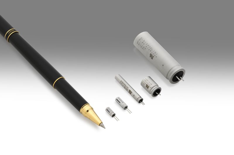 A pen and a set of capacitors of various sizes on a gray background.