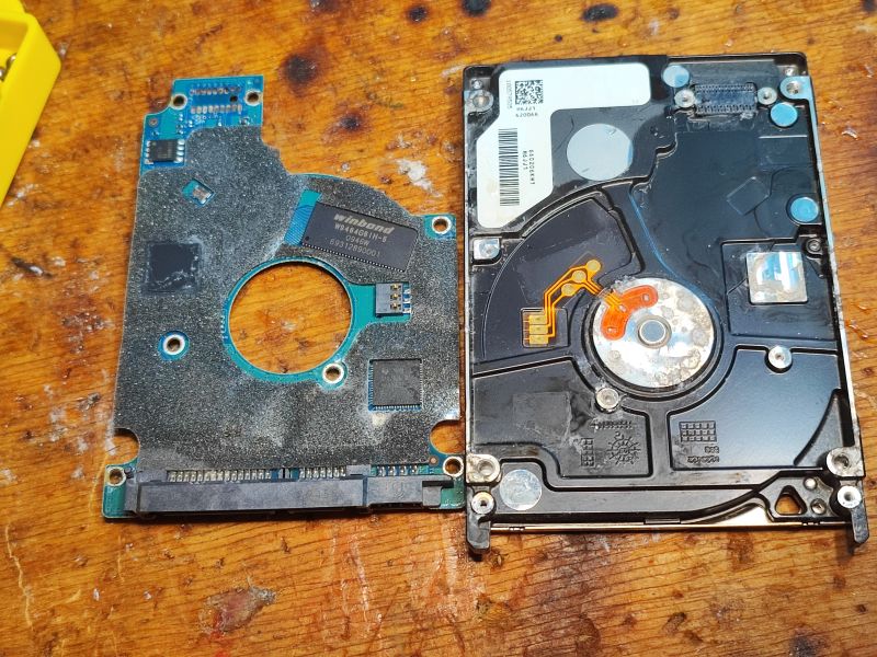 Interior and PCB of Seagate Momentus 5400.6 500GB HDD Printed circuit board and inside of a hard drive on a wooden table.