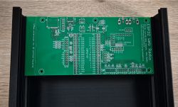 Green PCB with visible traces and component slots, placed on a wooden surface.