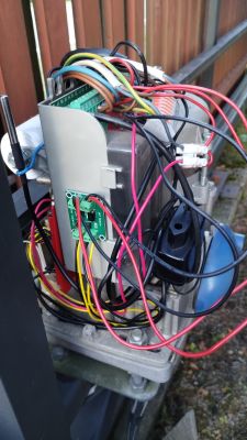 Układ elektryczny z wieloma przewodami i modułem Sonoff SV na tle drewnianego płotu.