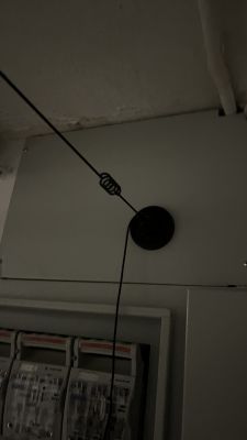 Antena zamontowana na rozdzielni elektrycznej z cienkim czarnym przewodem.