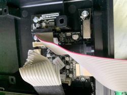 Zdjęcie wnętrza obudowy elektronicznej z widocznymi taśmami i komponentami.